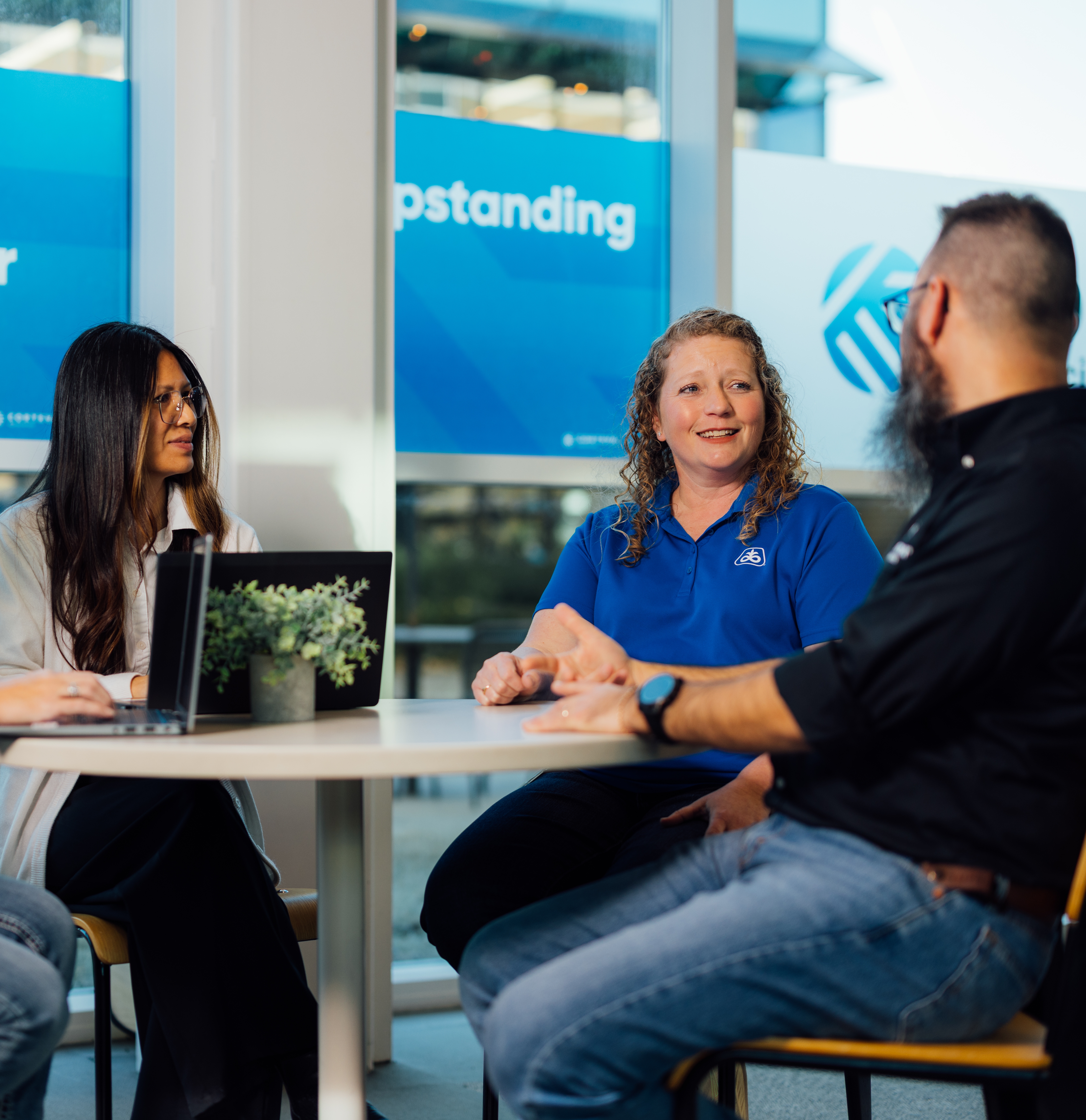 Three employees seated at table talking